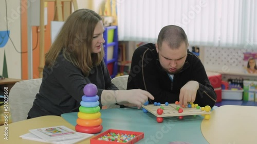 A female psychologist works with an adult boy with autism in the office. The concept of autism