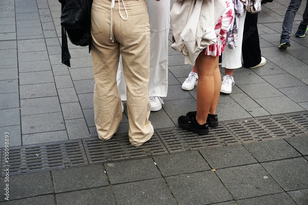 Gruppe Frauenbeine auf Gehweg in Stadt am Abend im Frühling 