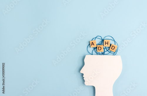 Silhouette of human head and wooden blocks with the letters ADHD on pastel background. Creative concept of attention deficit hyperactivity syndrome. Copy space photo
