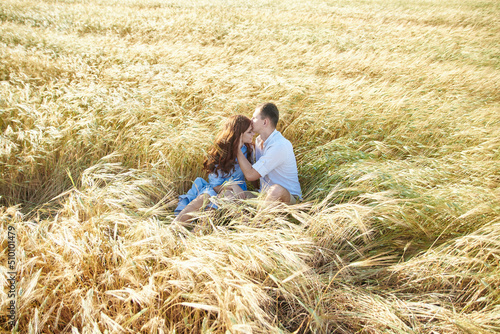 Lovely young couple kissing while sitting in a field. Love in the summer