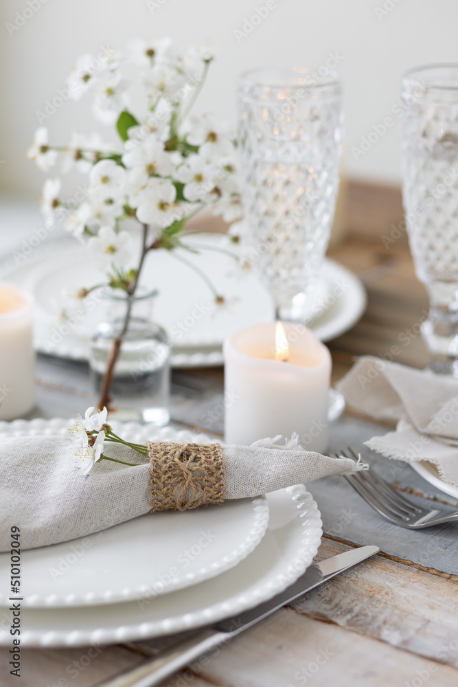 Rustic zero waste wedding decor with natural elements. Wooden table, candles, linen napkins, branches with green leaves. Eco-friendly decoration for the special dinner. Romantic and cozy place