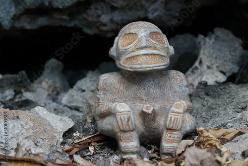 Taino Antique Stone Cemi Idol God Figure standing over rocks near a cave, close up. Taino Mythology. photo