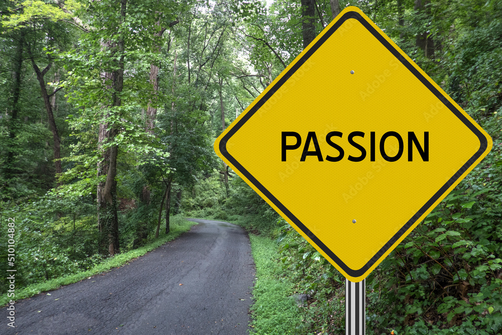 Passion sign with a road through the woods.