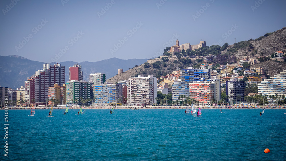 Panoramic view of the castle of the city of Cullera with people windsurfing in the foreground