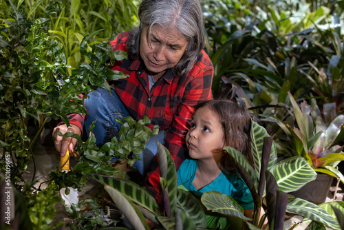 Gardening with children. Grandmother teaches her Latin American grandson to work in her home garden. Hobbies and leisure, lifestyle, family life.