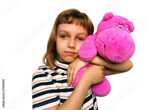 A cute Caucasian girl of 7 years old with blond hair cuddles and hugs a pink hippopotamus. Hippo plush toy. An expression of love, affection, favor. Game in daughters - mothers. Childhood adolescence. photo