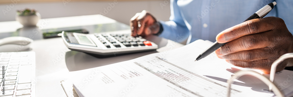 Smiling Businessman Calculating Invoice On Computer Smiling Businessman Calculating Invoice On Computer