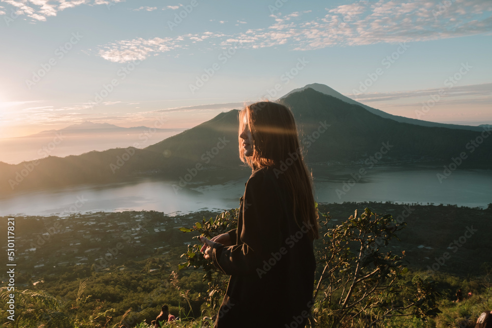 © Karyna Bartashevich/Stocksy - photo of a girl in profile during a beautiful sunset in Bali against the backdrop of a natural lake and mountains during sunset © Karyna Bartashevich/Stocksy - photo of a girl in profile during a beautiful sunset in Bali against the backdrop of a natural lake and mountains during sunset