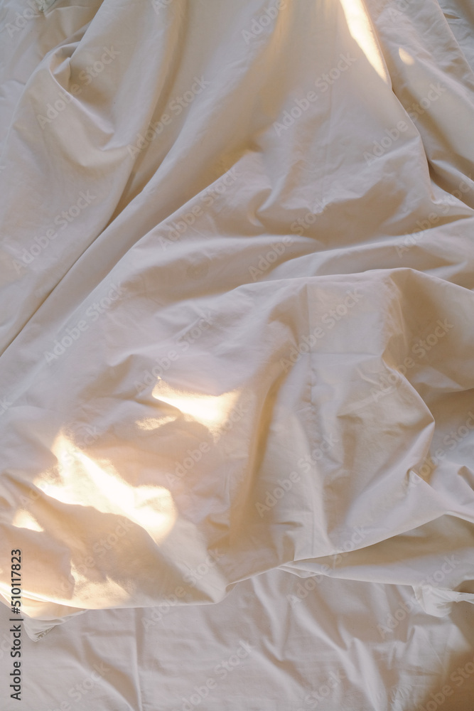 © Karyna Bartashevich/Stocksy - photo of a white wrinkled blanket in the morning on which sunlight falls in a hotel room in Bali
