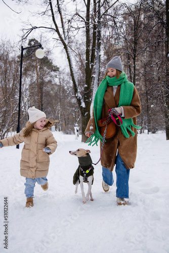 Mom, dog and kid runnung in a winter park photo