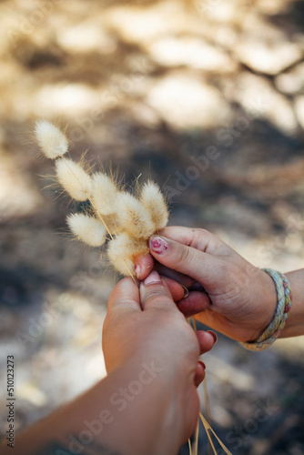 adult and child holding up bunny tail grass bouquet together photo