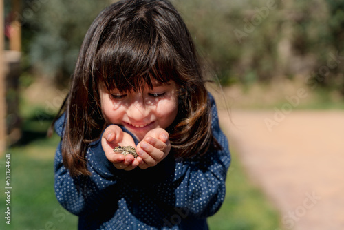 Happy little girl looking after a frog. Animal care photo