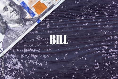 BILL - word (text) on a dark wooden background, money, dollars and snow. Business concept (copy space).