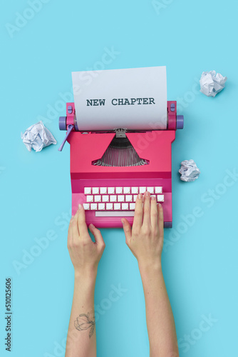 Woman typing text new chapter on vintage typewriter