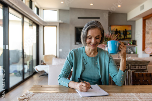 Woman Drinking Coffee Jots Down Her Ideas photo