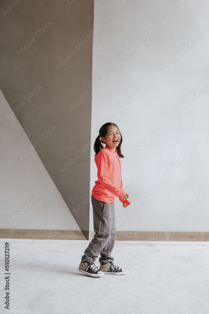 Young girl in workout clothes laughs near a concrete wall. Young girl in workout clothes laughs near a concrete wall.