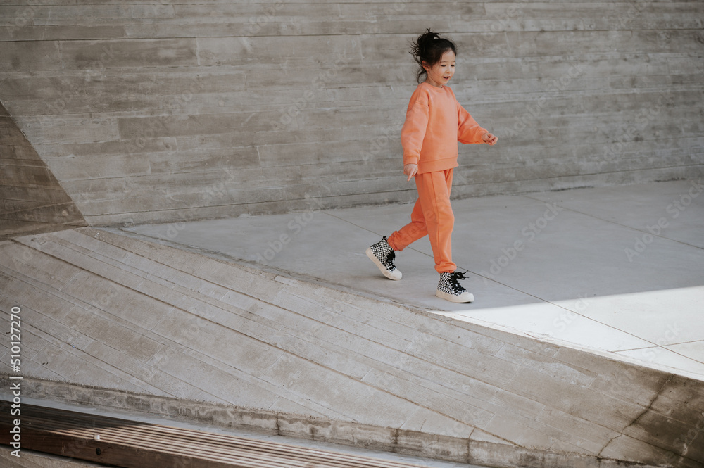 Young girl in workout clothes walks near a concrete wall. Young girl in workout clothes walks near a concrete wall.