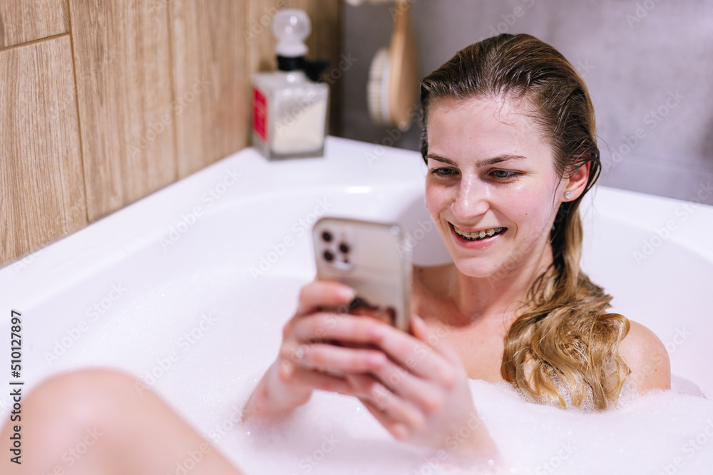 Happy girl using social networking on smartphone in bath Happy girl using social networking on smartphone in bath