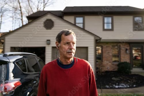 Retirement age man outside home with car