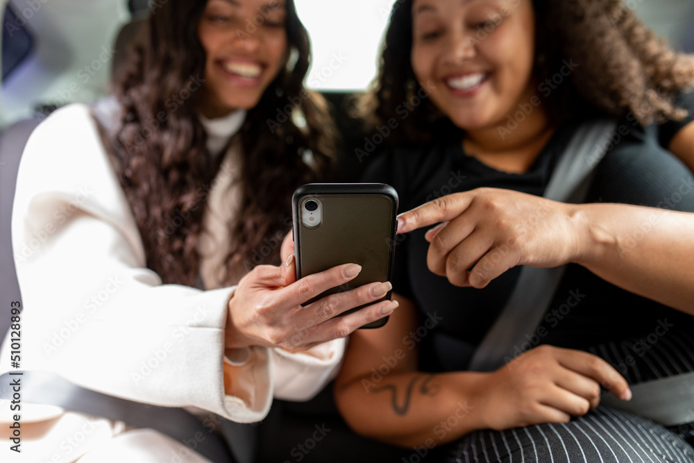 Women Look At Smartphone From The Backseat Of A CAr Women Look At Smartphone From The Backseat Of A CAr