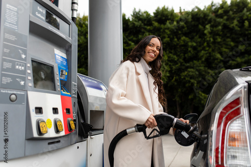 Young Woman Smiles As She Fills Her Vehicle With Gas photo