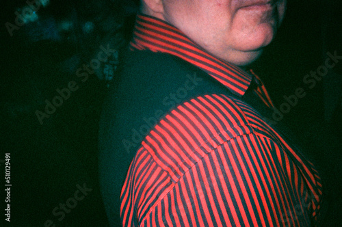 Man in a red striped shirt and black waistcoat photographed with flash photo