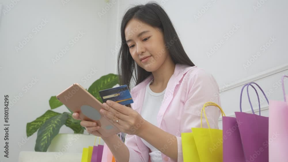 Young asian woman sitting on sofa using digital tablet shopping online with credit card buying to internet, happiness girl paying with transaction financial, purchase and payment, business concept. Young asian woman sitting on sofa using digital tablet shopping online with credit card buying to internet, happiness girl paying with transaction financial, purchase and payment, business concept.