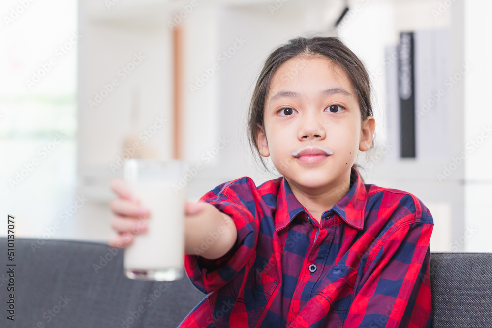 Happy child girl drinks milk, Portrait of Asian little cute kid holding a cup of milk in kitchen Happy child girl drinks milk, Portrait of Asian little cute kid holding a cup of milk in kitchen