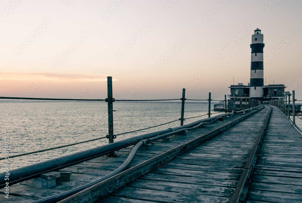  Faro y plataforma en medio del mar, colores anaranjados