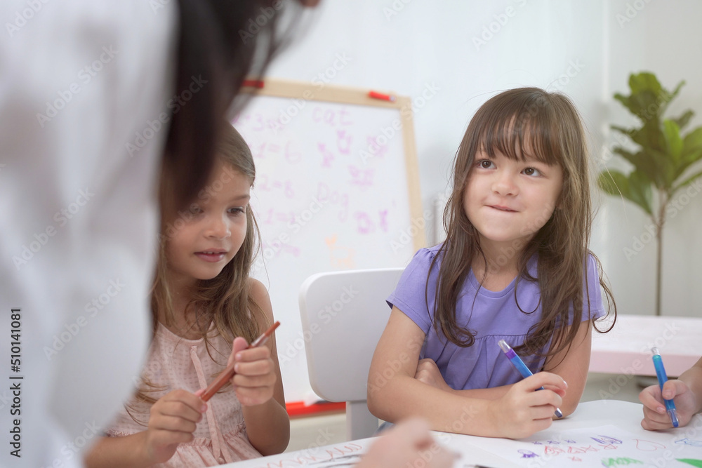 Happy caucasian and Asian young elementary school age enjoy learning and playing in their classroom. Happy caucasian and Asian young elementary school age enjoy learning and playing in their classroom.