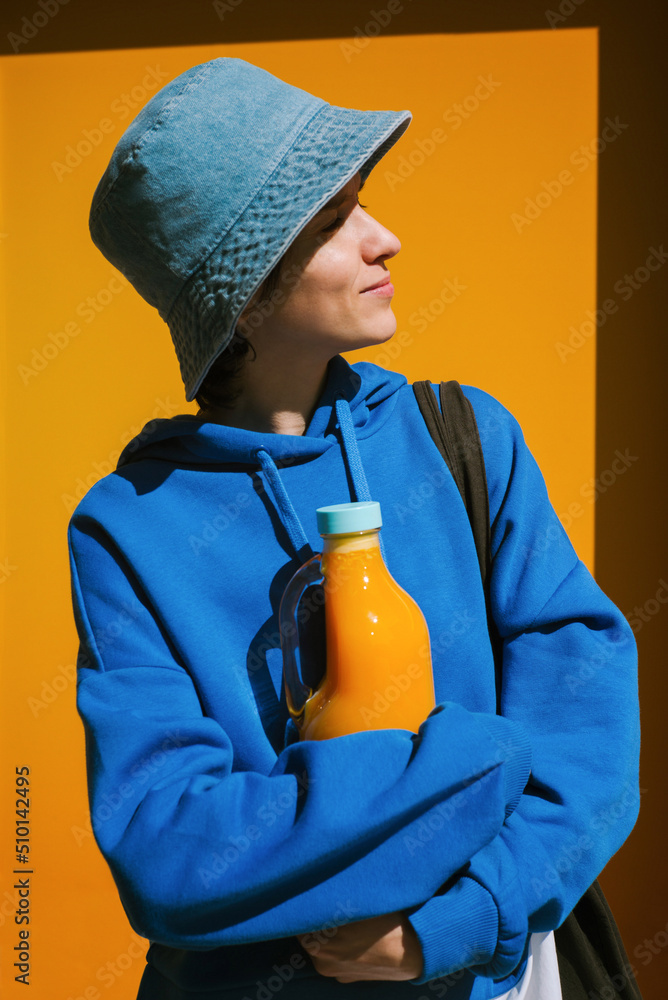 Young woman holding big glass bottle with squeezed orange juice Young woman holding big glass bottle with squeezed orange juice