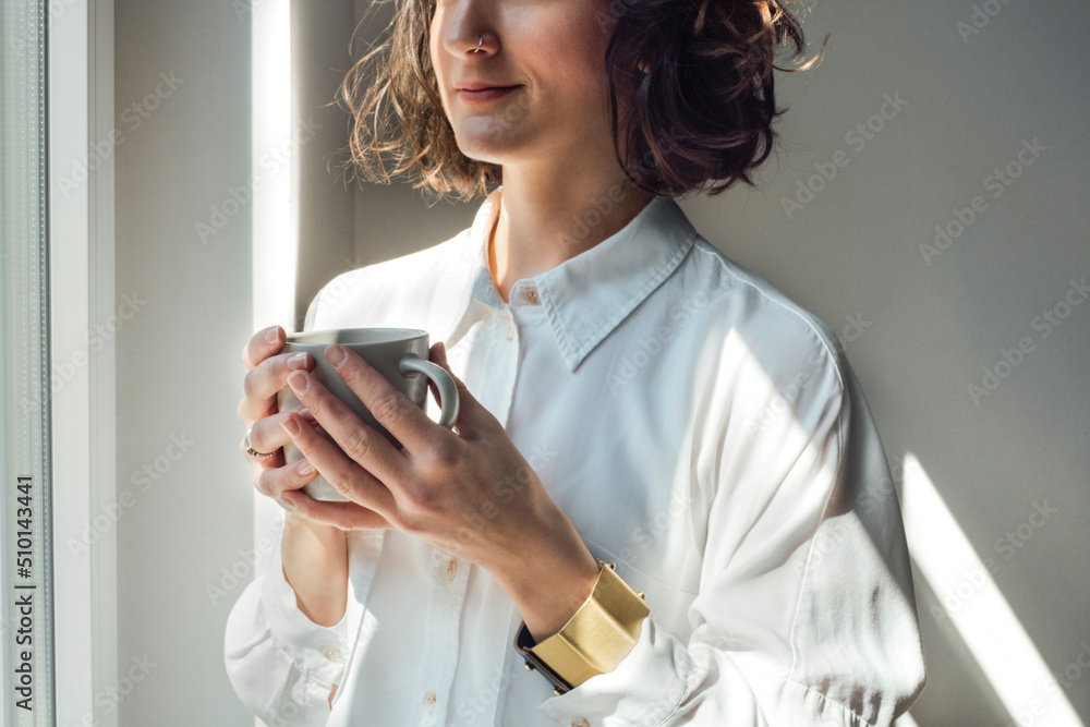 Cropped Image of Woman Looking Out the Window and Holding Coffee Cropped Image of Woman Looking Out the Window and Holding Coffee