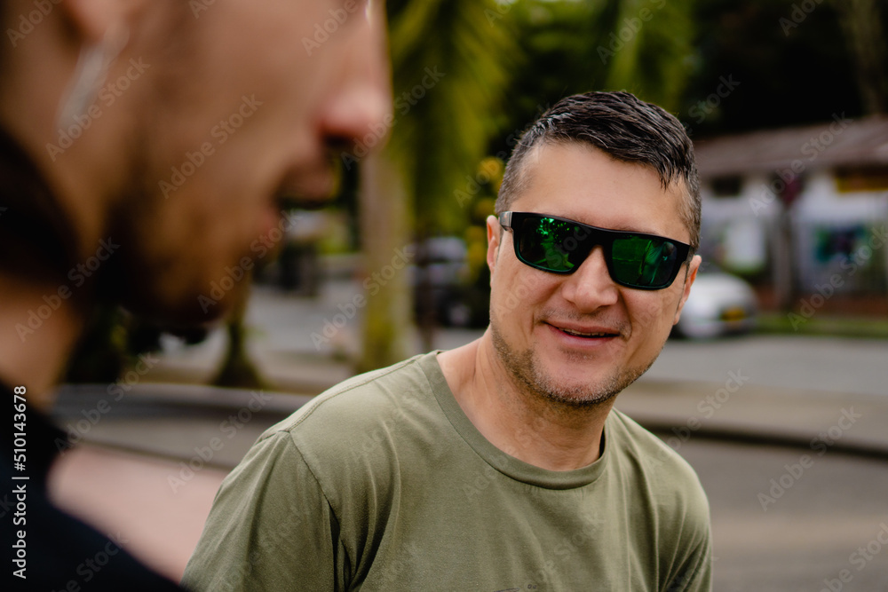 latin man in his forties with sunglasses smiling talking to friends in the street