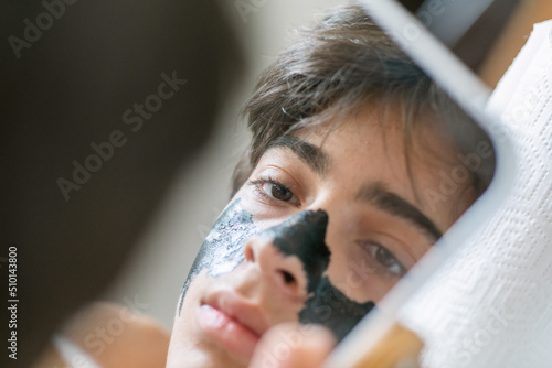 Teen boy looking into small mirror 