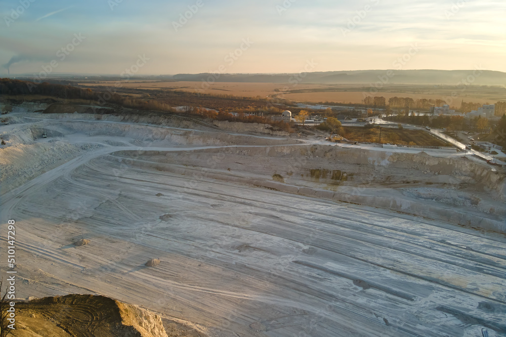 Aerial view of open pit mine of sandstone materials for construction industry with excavators and dump trucks. Heavy equipment in mining and production of useful minerals concept