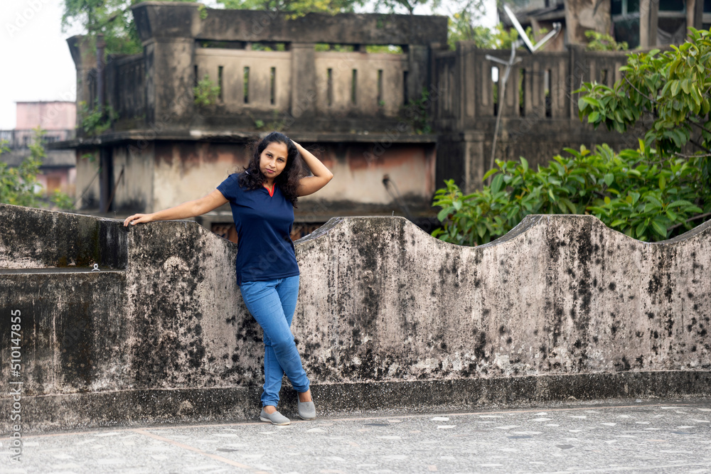 A woman wearing jeans and T shirt standing on rooftop of a building A woman wearing jeans and T shirt standing on rooftop of a building