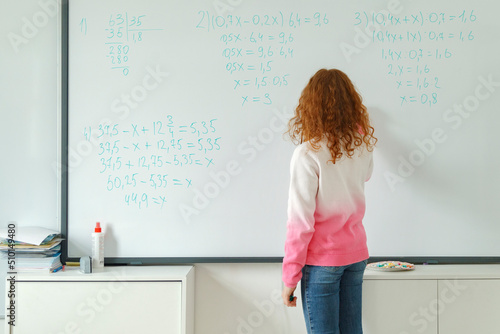 Girl solving equations on whiteboard photo