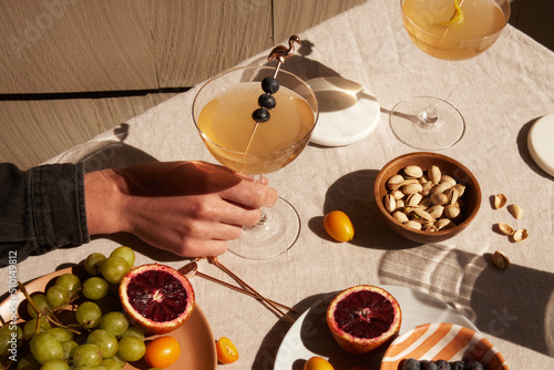 Person holding a cocktail glass among different foods