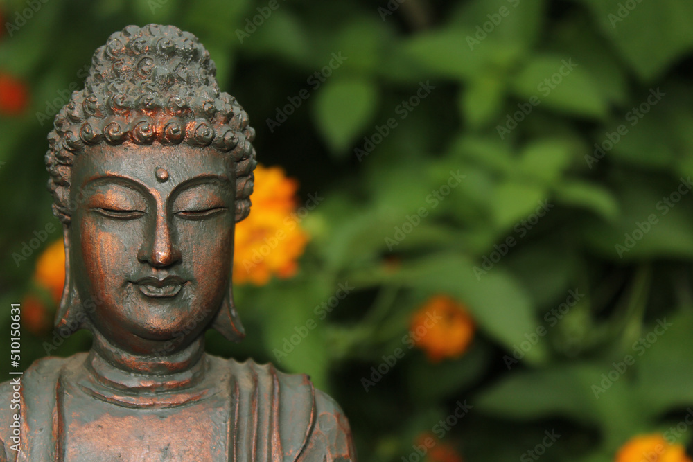 Buddha Statue in Garden with blurred flowers in background