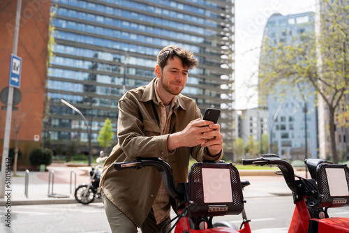 Bearded man with phone renting bike at city photo
