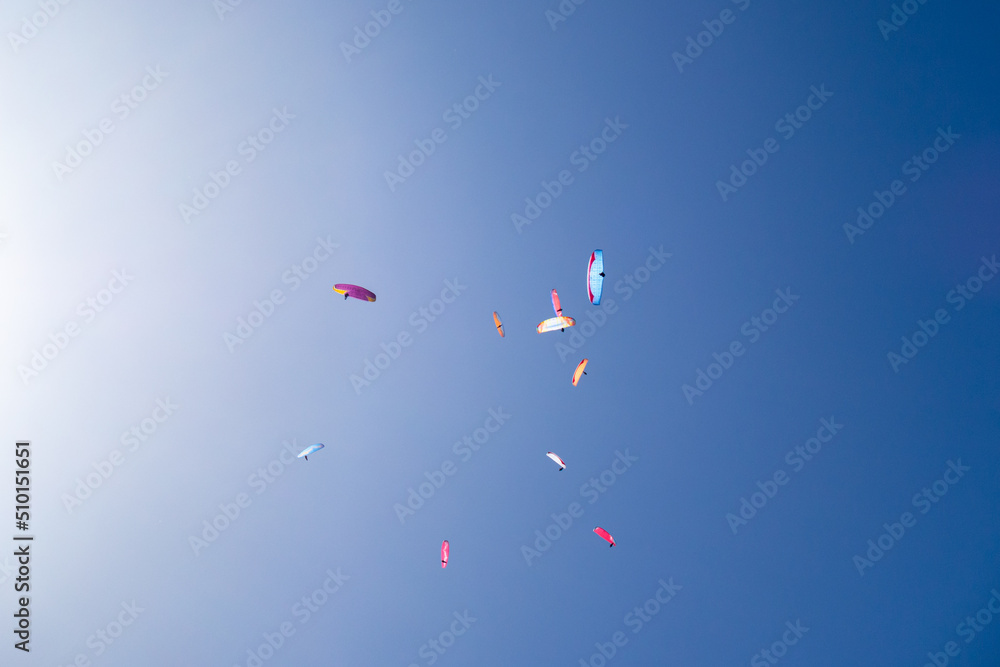 cluster of colourful paragliders in a blue sky cluster of colourful paragliders in a blue sky