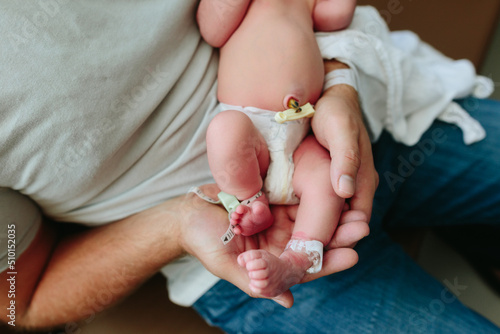 Dad holds tiny foot of newborn baby photo