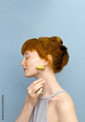 Woman Massaging Face With Green Quartz Jade photo