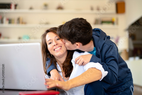 Son kissing working mother on cheek photo