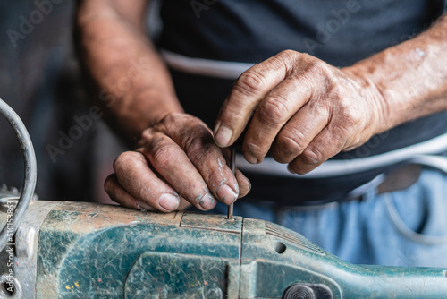 Hands of an old man repairing a machine photo