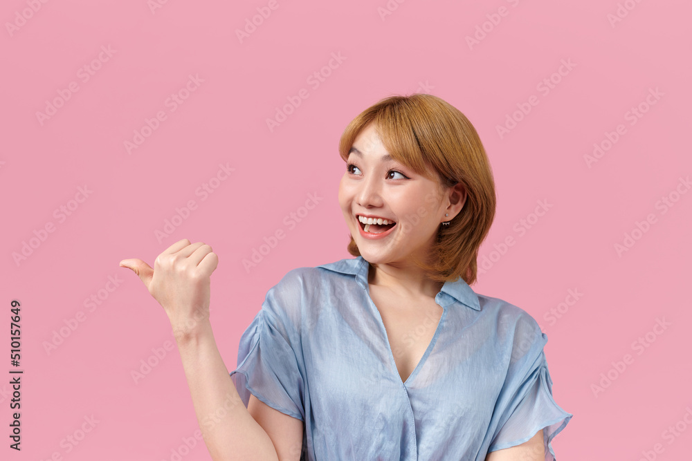 Young asian woman isolated on pink background points with thumb Young asian woman isolated on pink background points with thumb