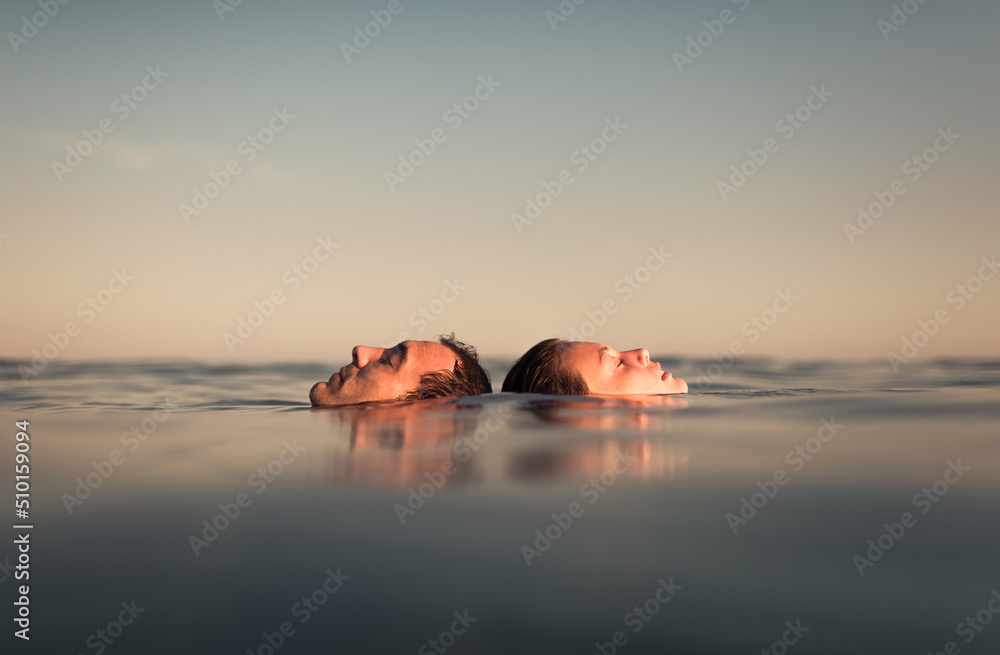 Relaxed couple floating together on the sea enjoying the calm Relaxed couple floating together on the sea enjoying the calm