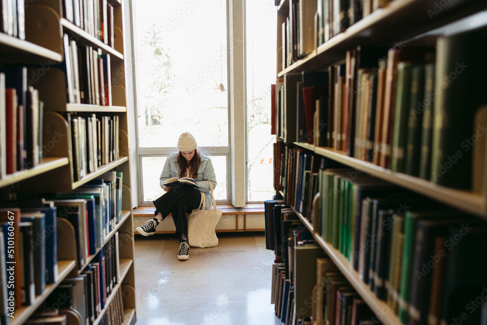 Young woman reading in library at college. Young woman reading in library at college.