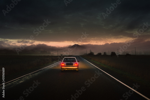 Car driving on cinematic road across natural misty scenery photo