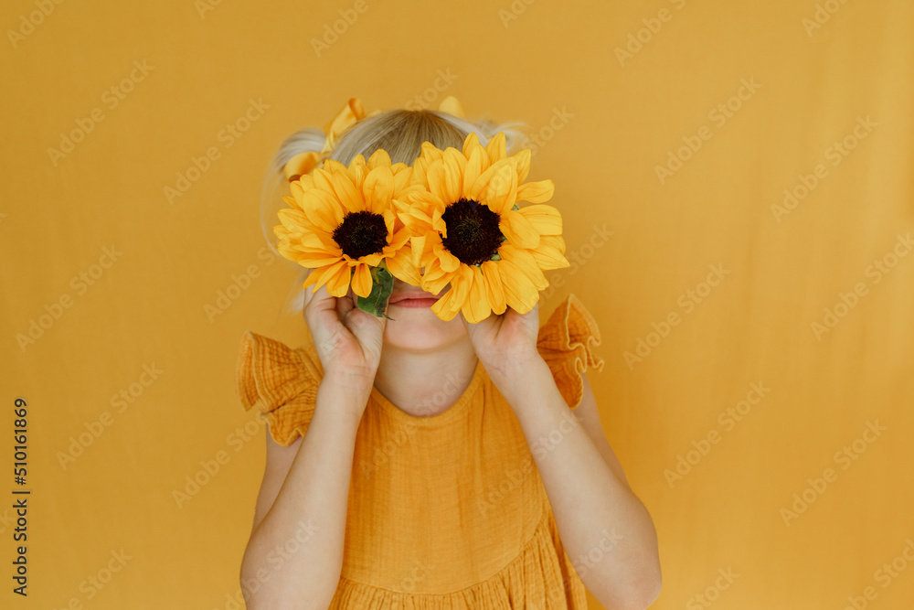 Portrait of a little girl over yellow backdrop with sunflowers Stock ...